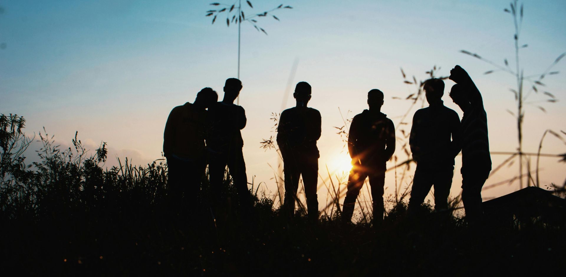 A group of friends silhouetted against the sunset, enjoying a moment in nature.