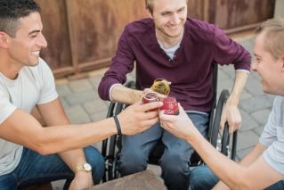 Three friends toasting with drinks outdoors, embracing friendship and joy.